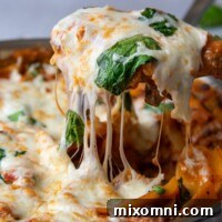 a spatula pulling up a serving of skillet lasagna with cheese dripping down