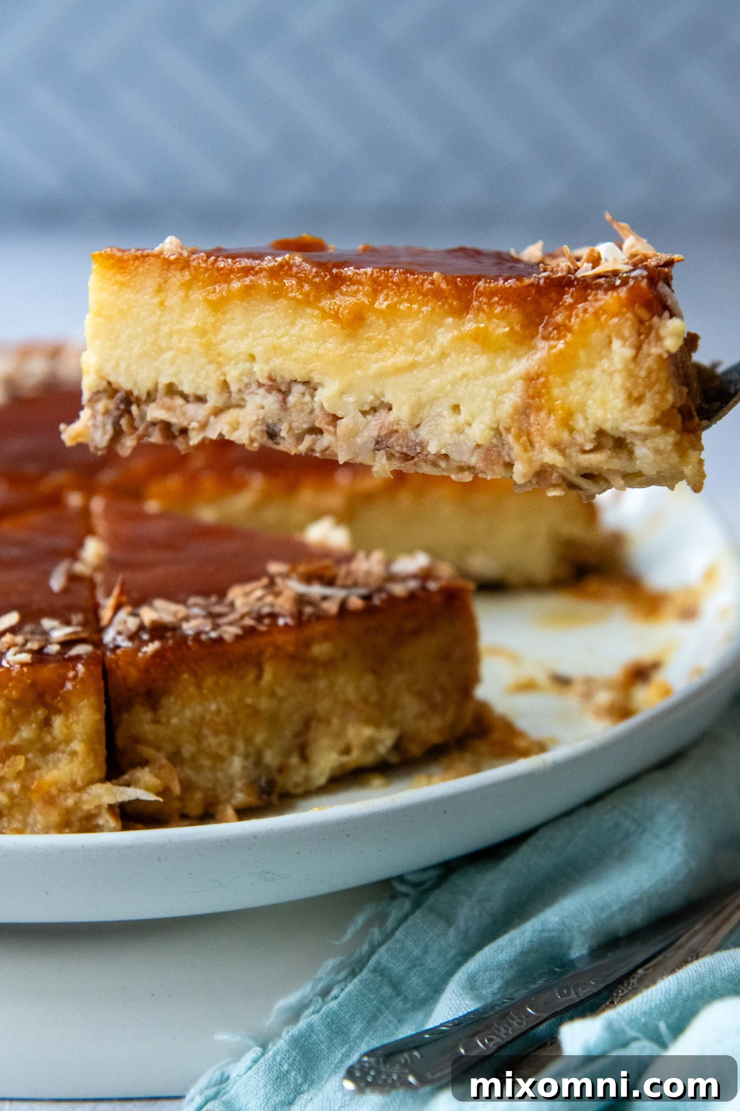 A perfectly sliced piece of coconut flan, showcasing its distinct layers, being gently lifted from a white plate by a fork, ready to be enjoyed.