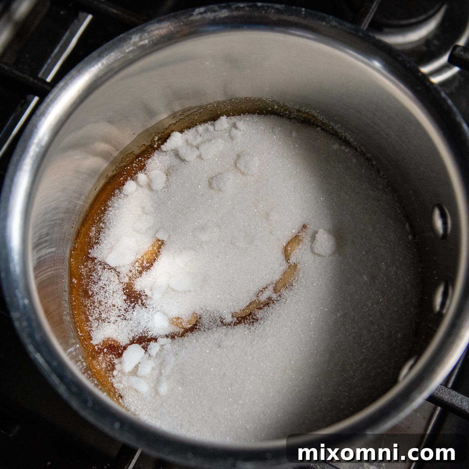 Granulated sugar beginning to melt and caramelize in a heavy-bottomed saucepan over medium heat, showcasing the initial stage of caramel creation.