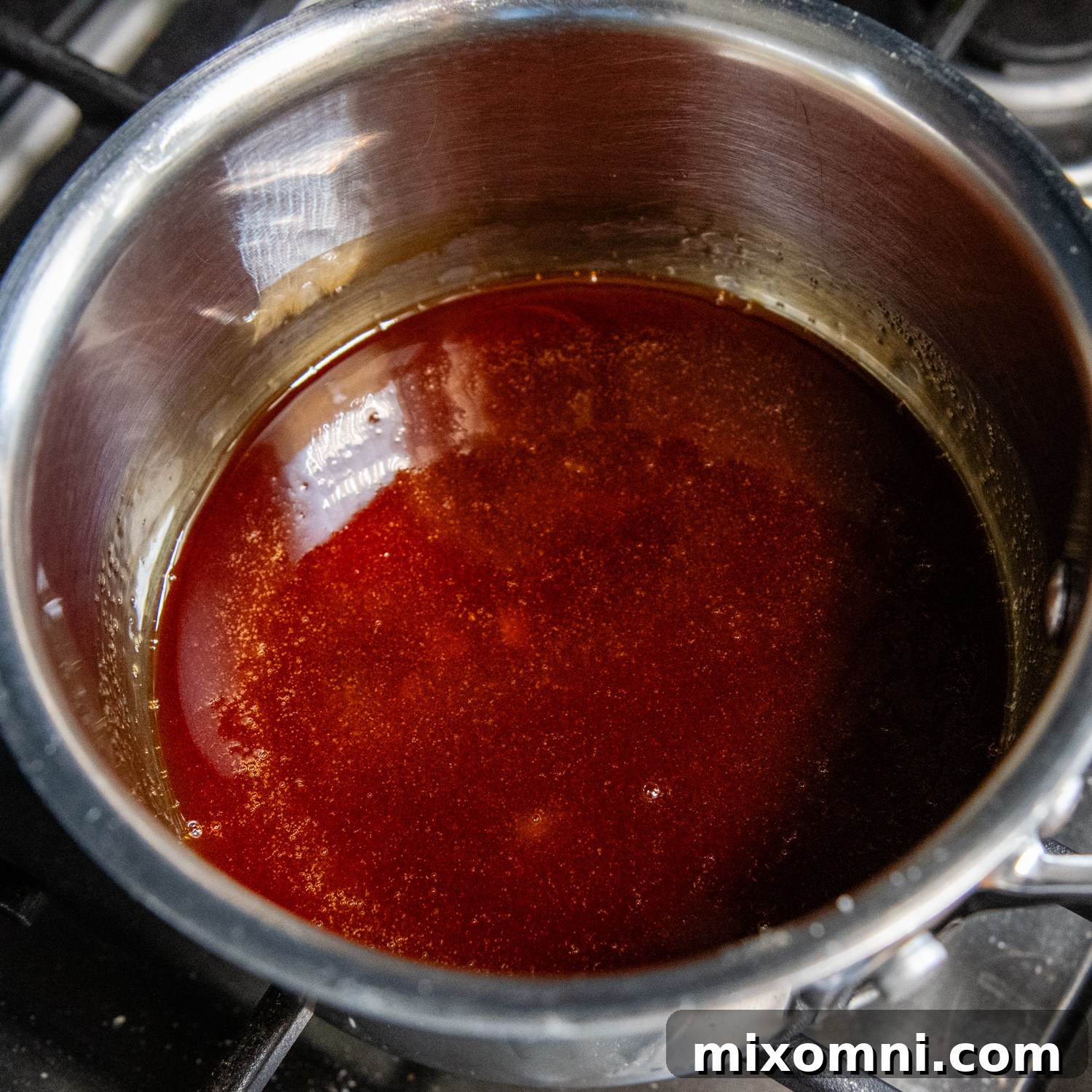 Perfectly melted and darkened caramel swirling in a saucepan, demonstrating the ideal amber color and smooth consistency before pouring into the flan pan.