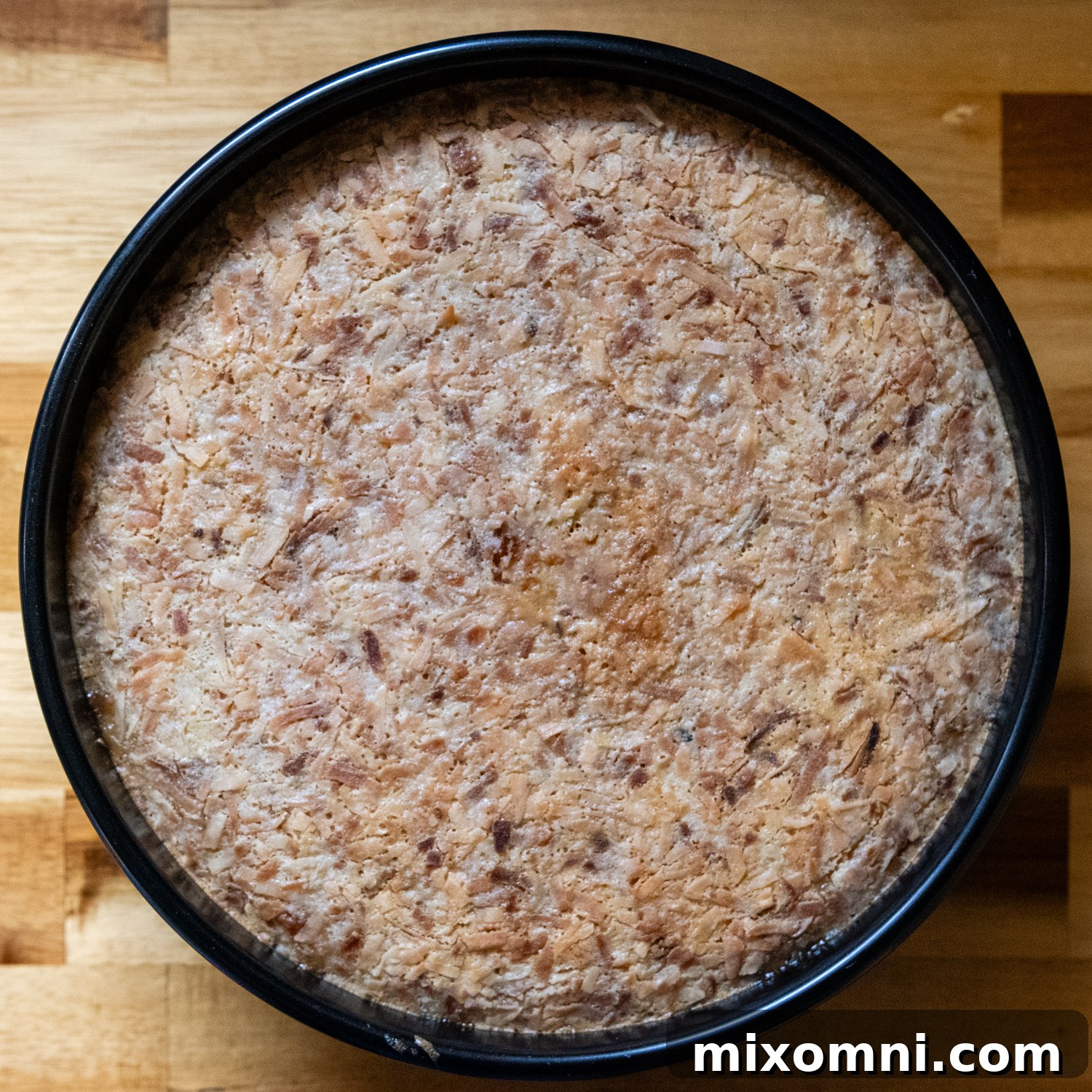 A flan pan nestled within a larger roasting pan, filled with hot water for a water bath, ready to be carefully transferred into the oven for baking.