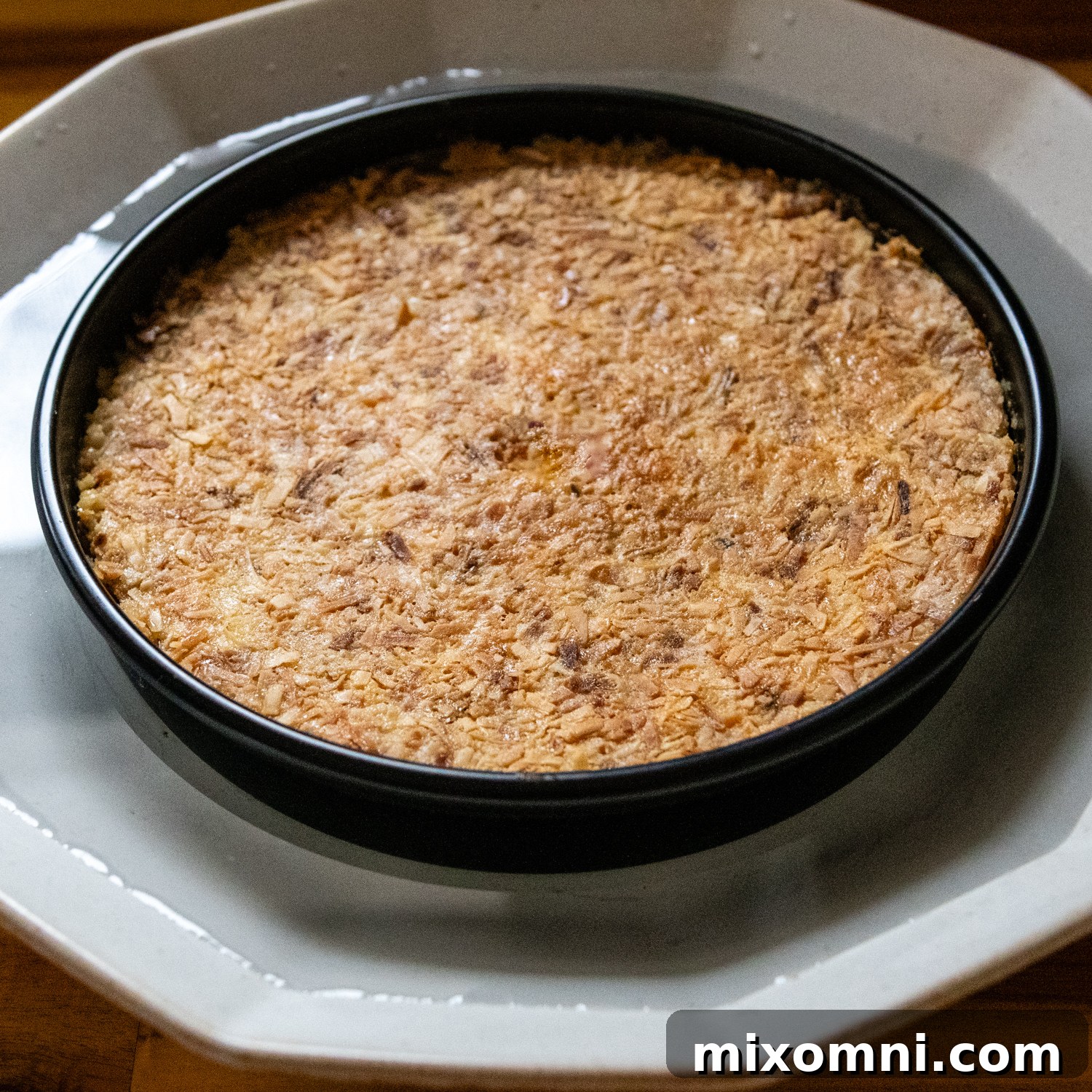 The baked and cooled flan, still in its pan, placed in a larger pan of warm water to gently loosen the caramel before inversion.