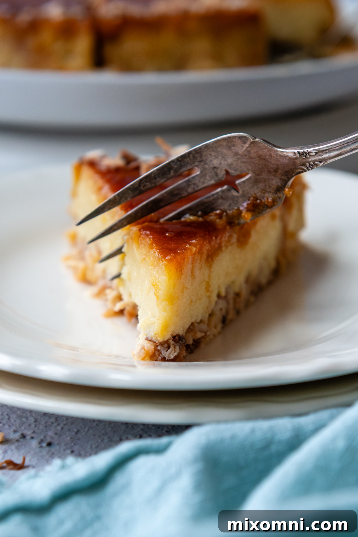 A fork gently cutting into a slice of coconut flan, highlighting its tender texture and layered appearance.