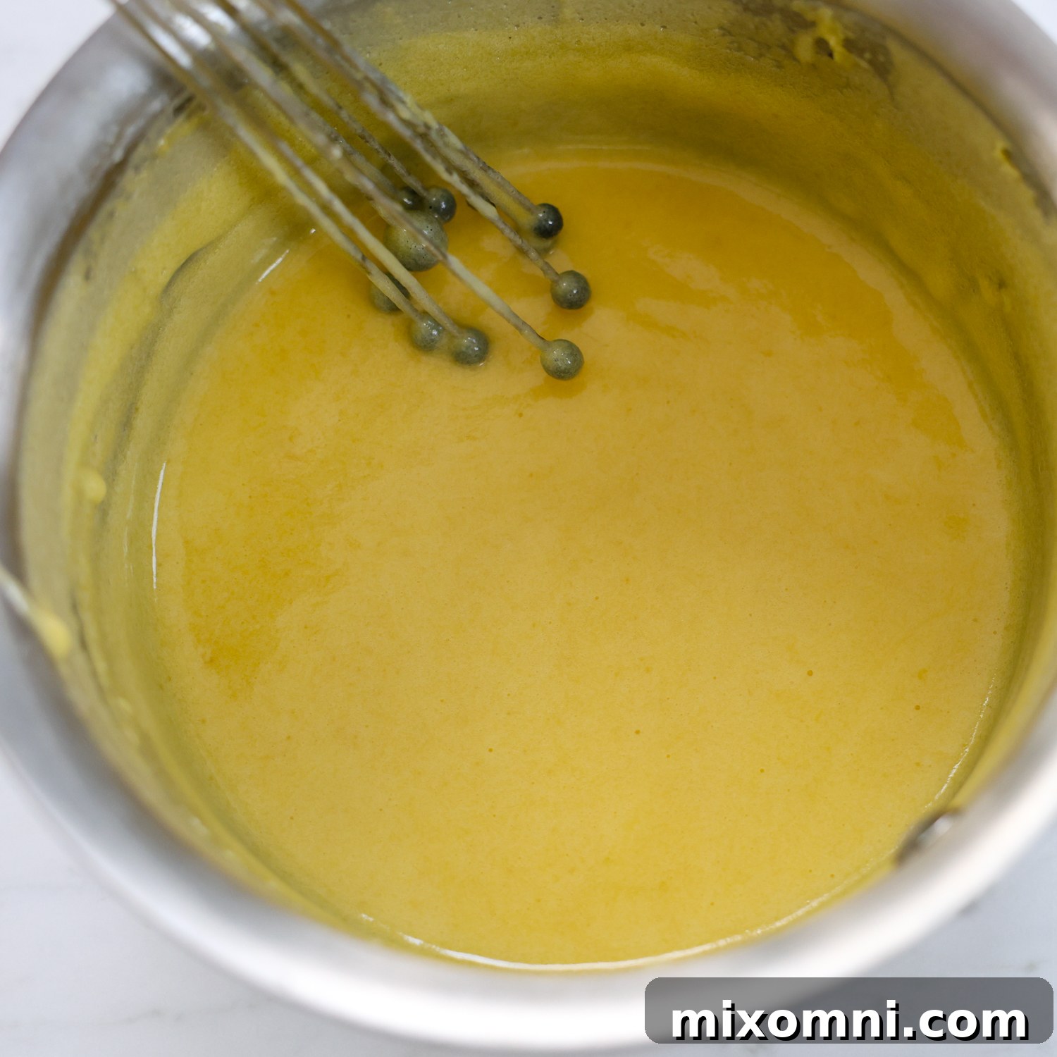 Egg yolks, sugar, and milk mixture in a glass bowl, ready to be cooked into custard.