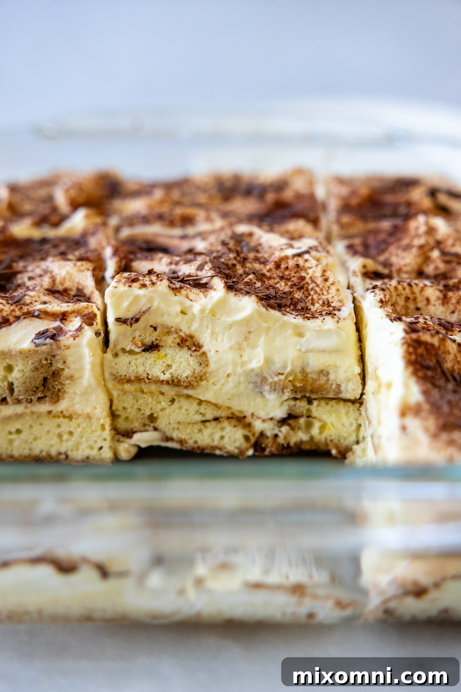 A large tiramisu in a glass baking dish, dusted with cocoa powder and ready to be served.