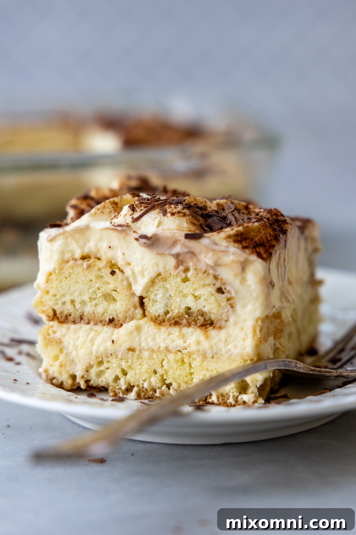 A beautiful side shot of the tiramisu, clearly showing the distinct layers of cream, espresso-soaked ladyfingers, and cocoa powder.