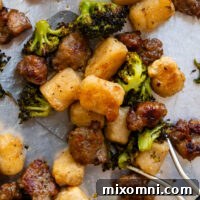 Close up of cooked crispy gnocchi, roasted broccoli and browned Italian sausage on a metal spatula.