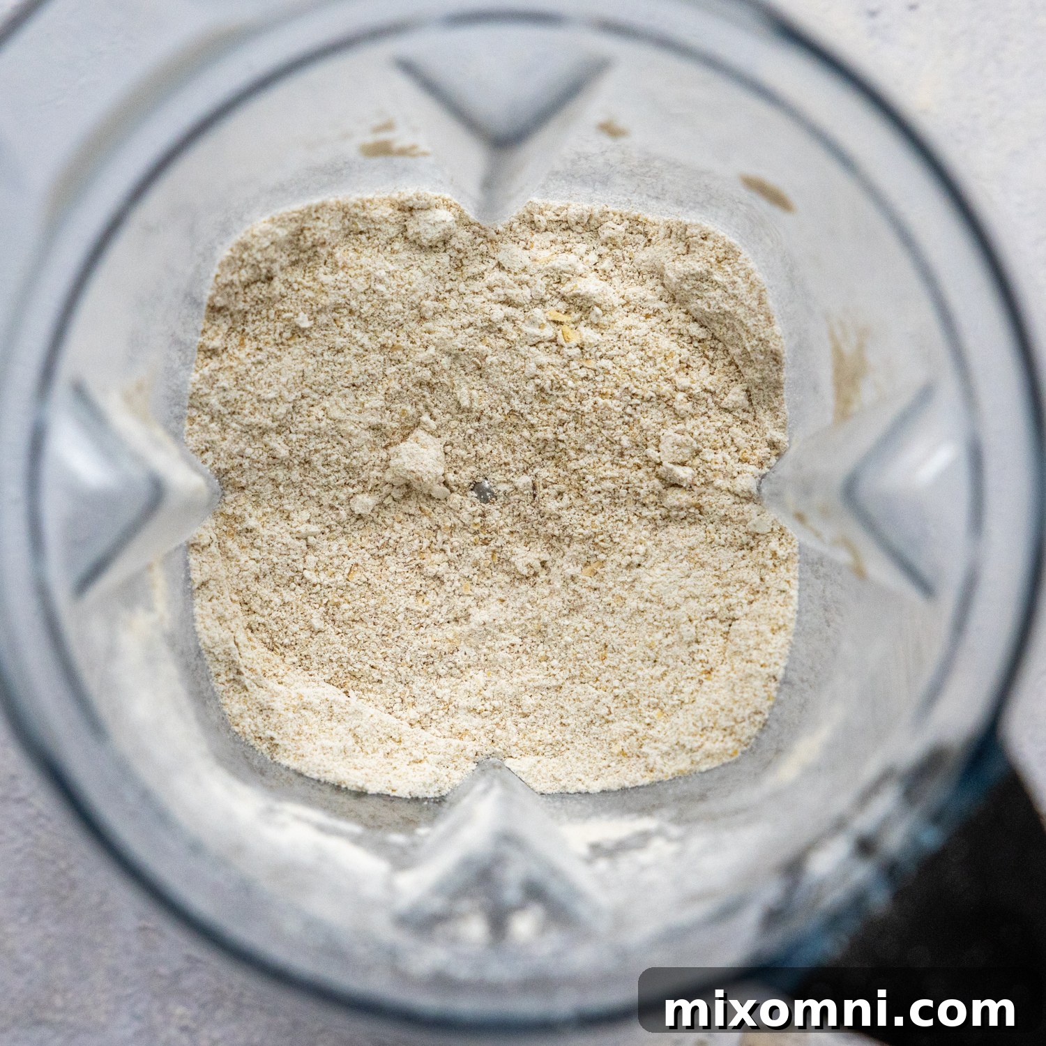 Gluten-free rolled oats being processed into fine oat flour in a high-speed blender.