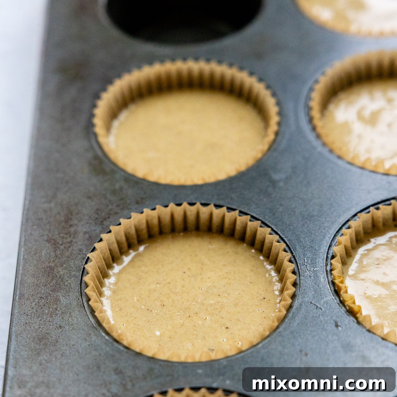Muffin batter neatly poured into muffin cups, ready to be rested and baked.