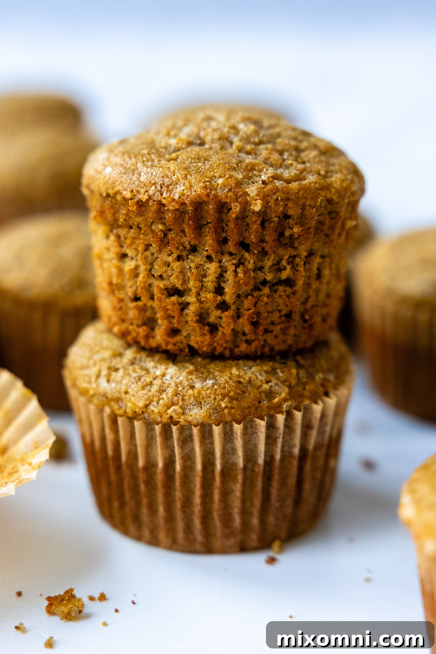 Two perfectly baked, tall banana oat muffins stacked on top of each other, showcasing their fluffy texture.