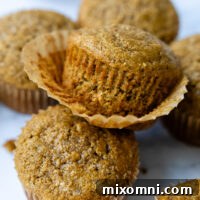 A stack of muffins with the wrapper coming off the top muffin showing texture.