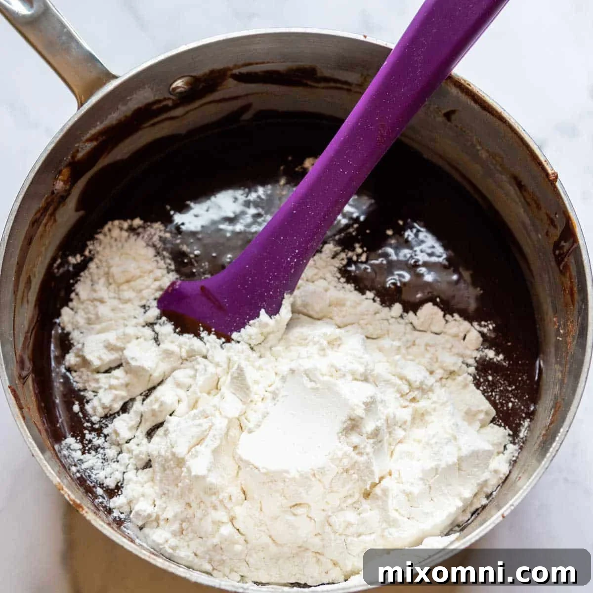 Gluten-free flour being stirred into the rich, chocolate brownie batter.