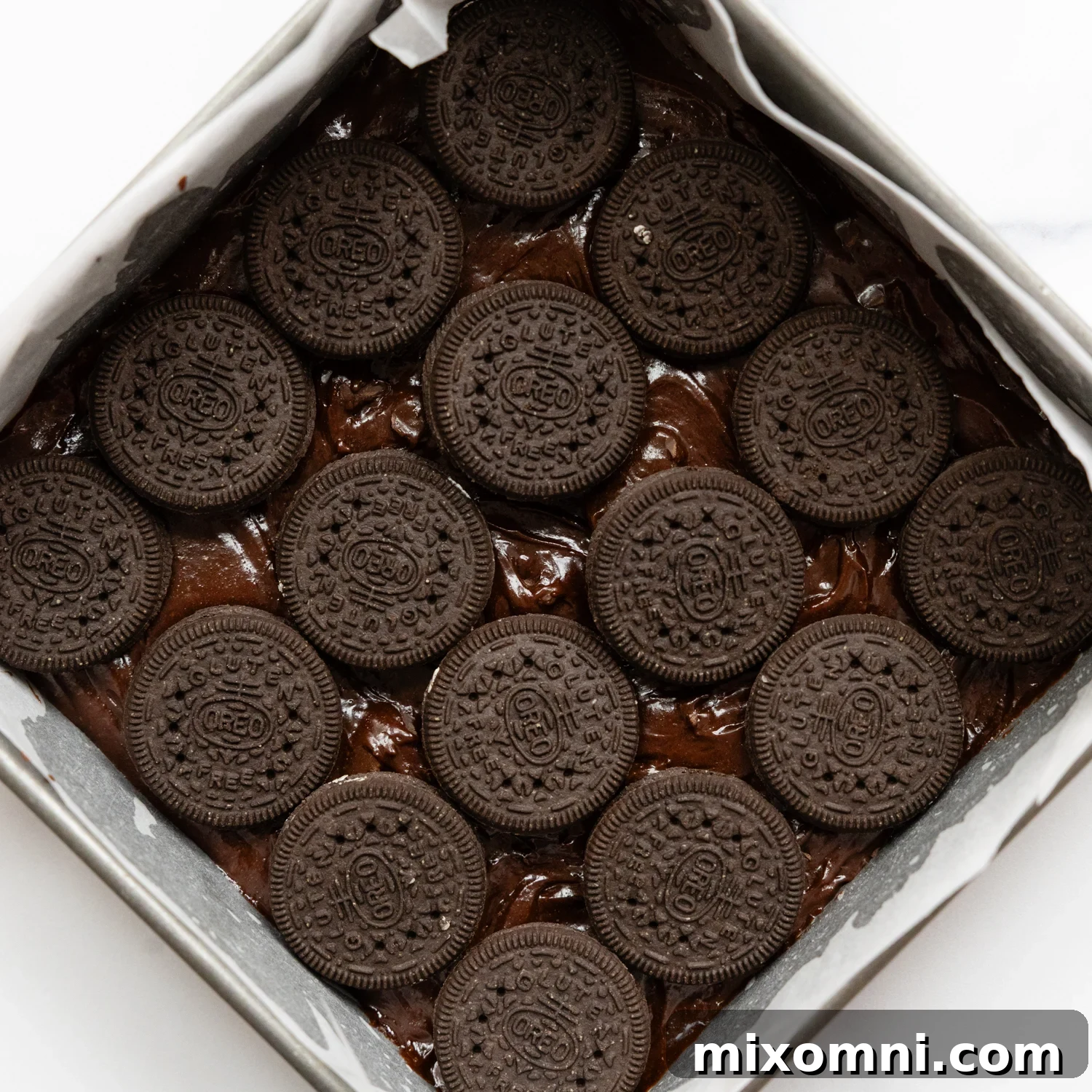 Gluten-free Oreos laid out in the bottom of a baking dish, nestled in brownie batter.