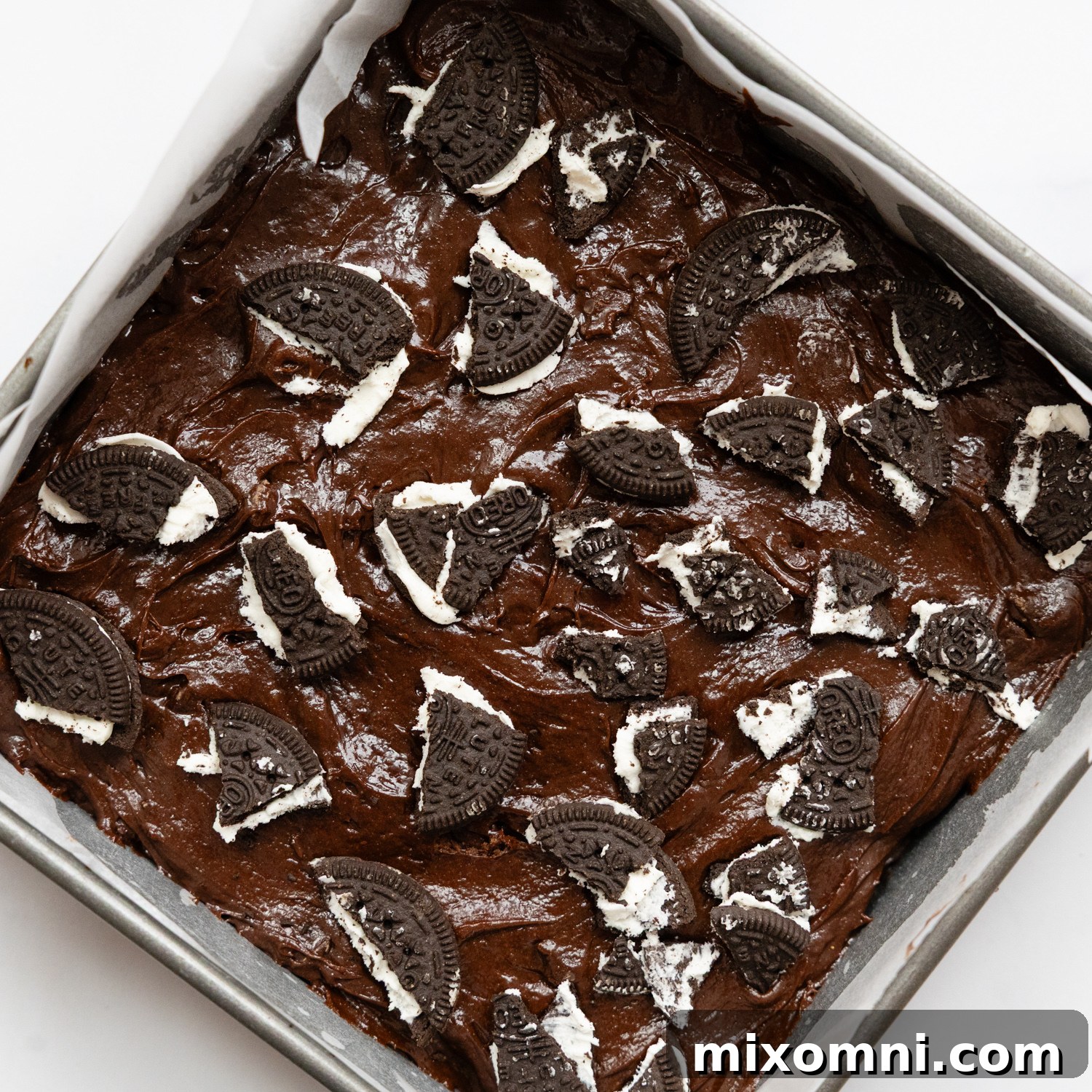 Gluten-free Oreo pieces sprinkled on top of brownie batter before baking.