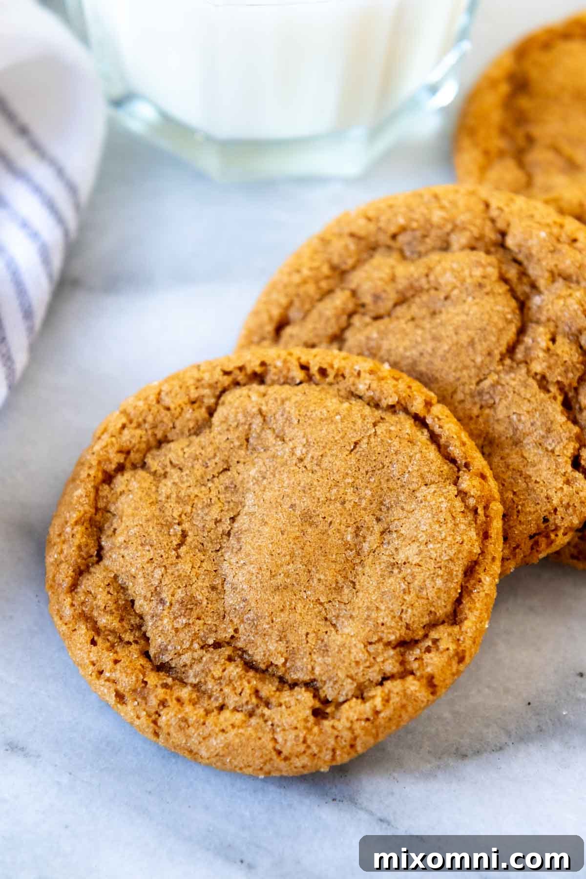 Irresistible gluten-free ginger snaps perfectly arranged next to a refreshing glass of milk, highlighting their soft and chewy texture and classic crinkled appearance.