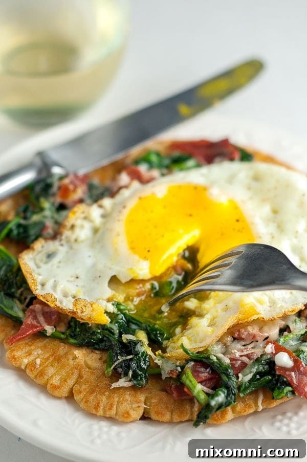A close-up shot of a fork cutting into the soft, runny yolk of an egg atop a Farinata pizza with spinach and prosciutto.