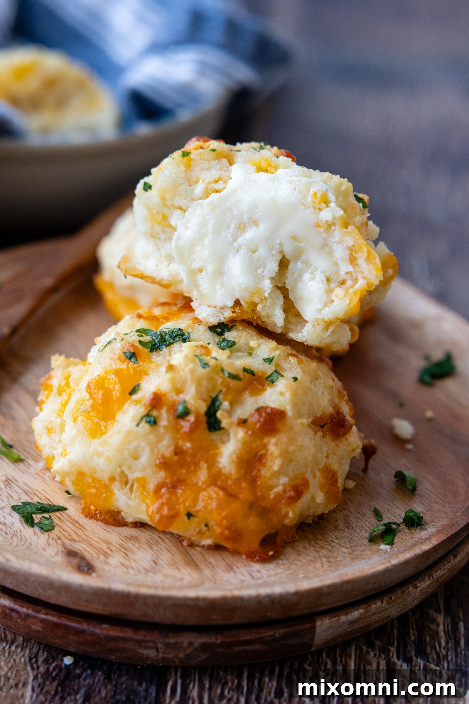 A basket full of freshly baked gluten-free cheddar biscuits, with some in focus and others in the background.