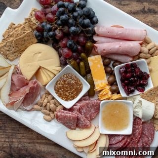 an overhead shot of a charcuterie board with plates nearby