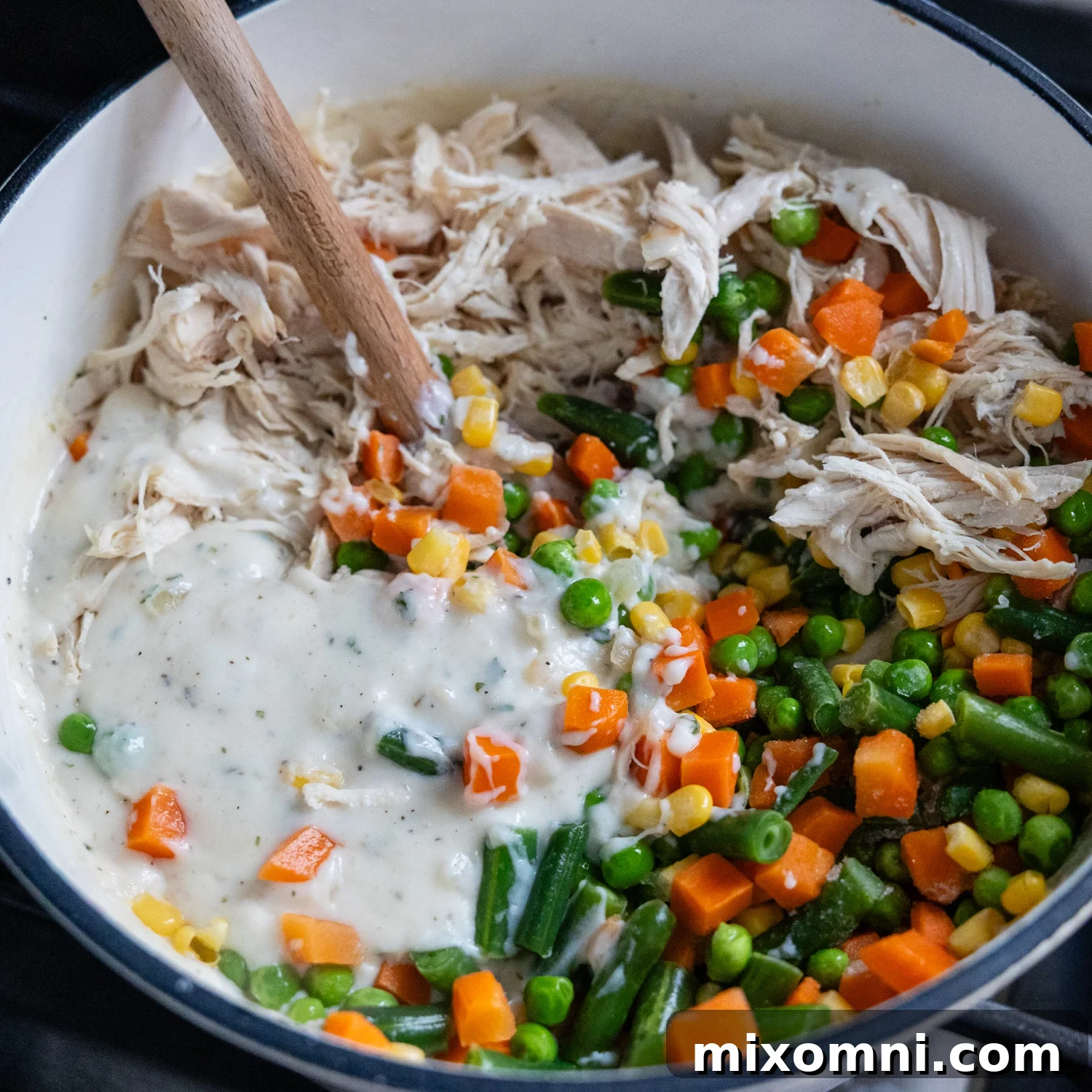 Chicken and veggies being added to sauce.