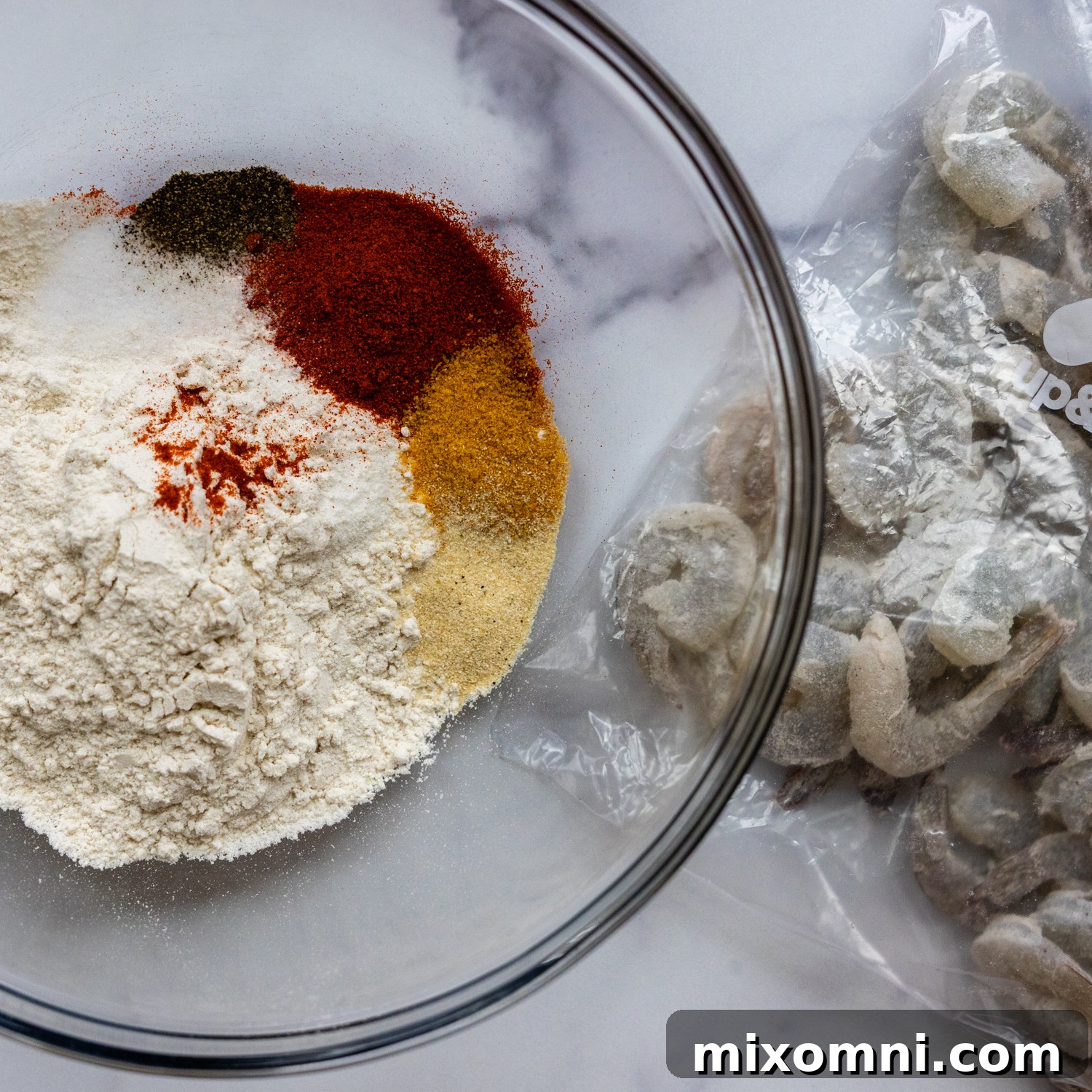 Dry batter ingredients, including gluten-free flour and spices, mixed in a glass bowl.