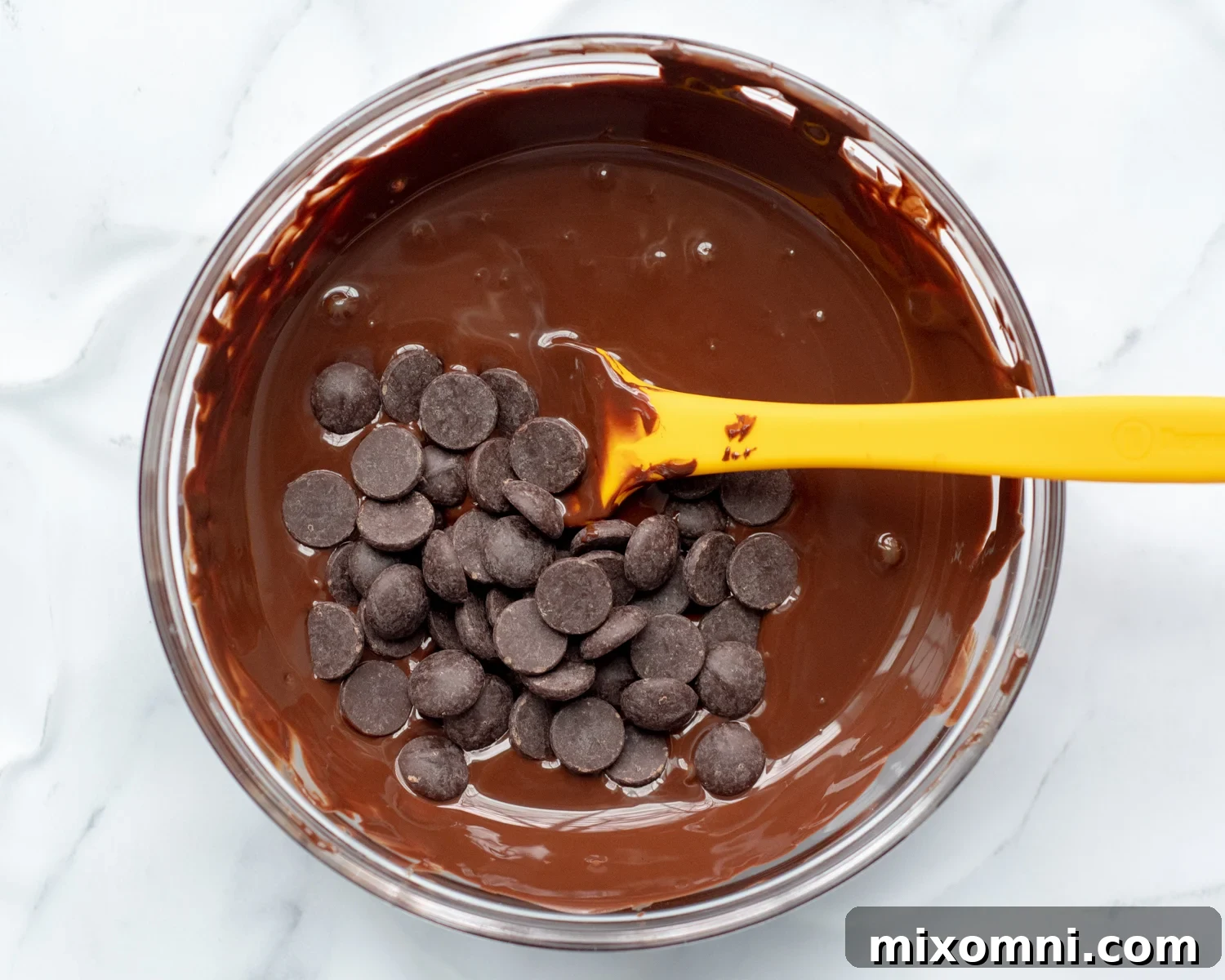 Close-up of chocolate chips melting in a bowl, showcasing the smooth, glossy texture of tempered chocolate.