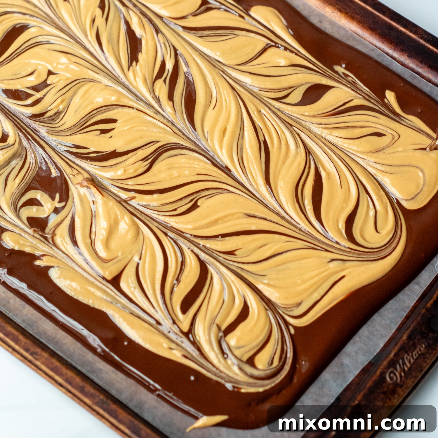 Melted chocolate and peanut butter swirled together on a baking sheet, showcasing the tiger stripe effect.