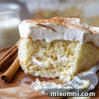 A delicious slice of tres leches cake on a wooden plate, showing its moist interior.