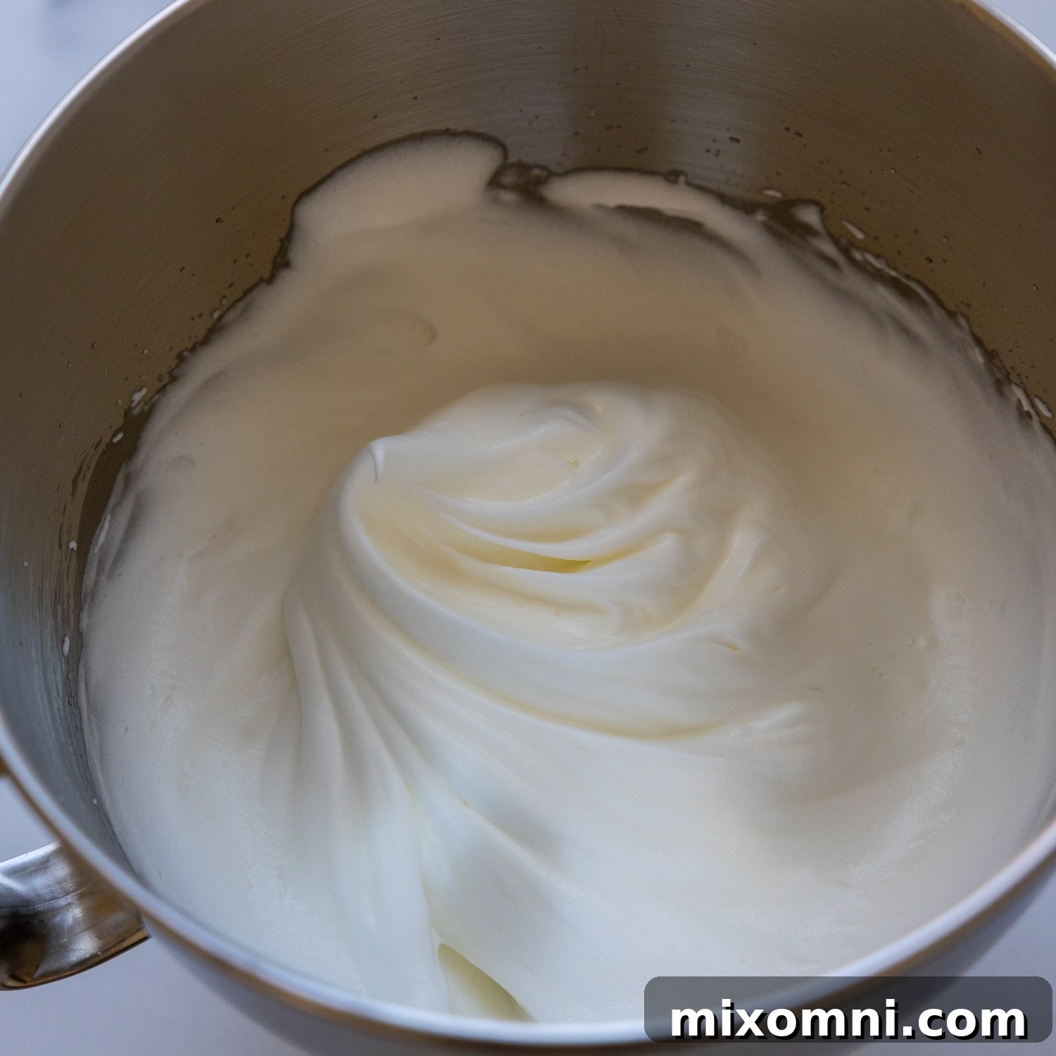 Foamy, stiff egg whites in a mixing bowl, ready to be incorporated into the cake batter.