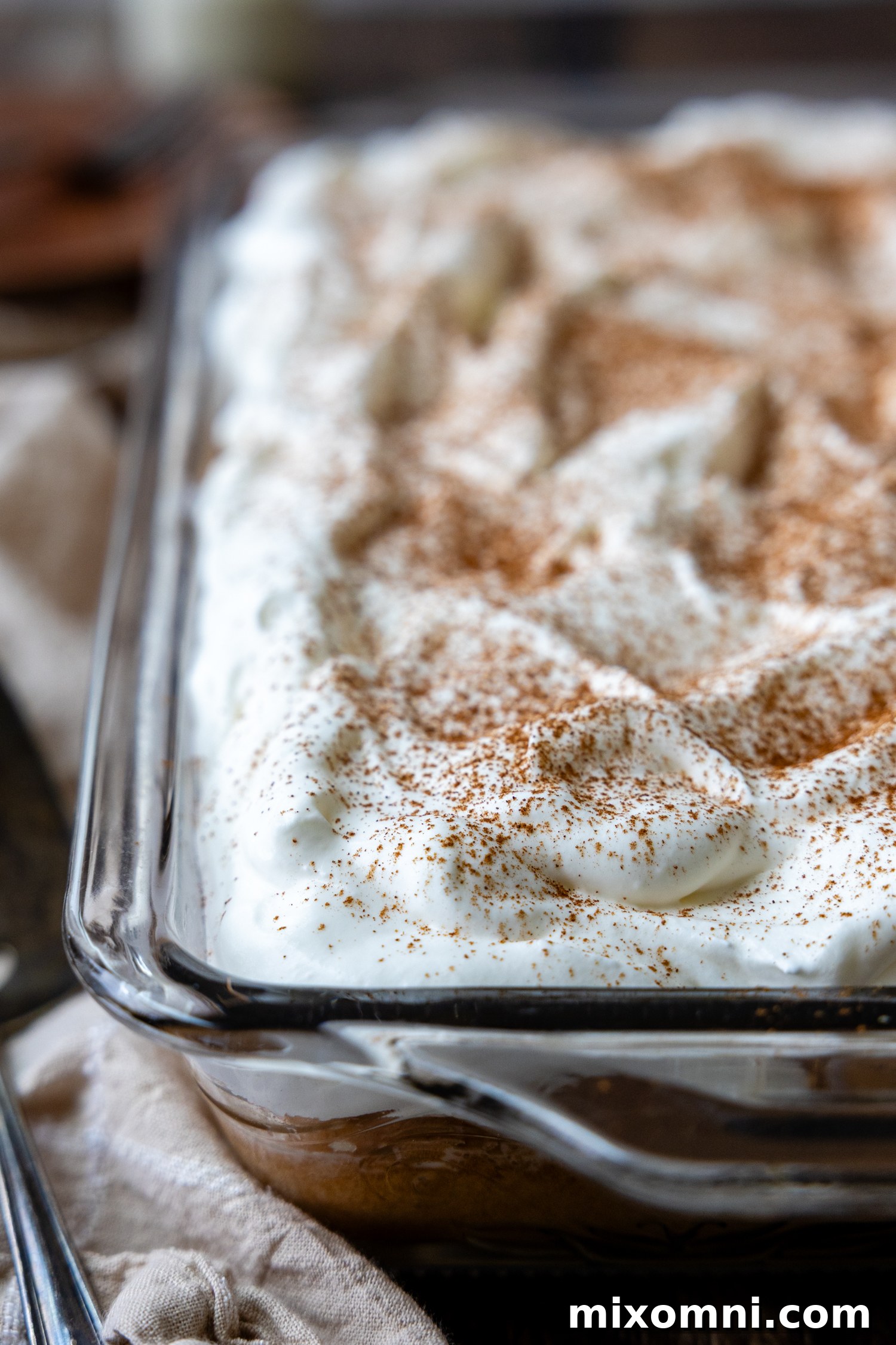 A finished gluten-free tres leches cake, beautifully topped with frosting, in a clear glass baking pan.