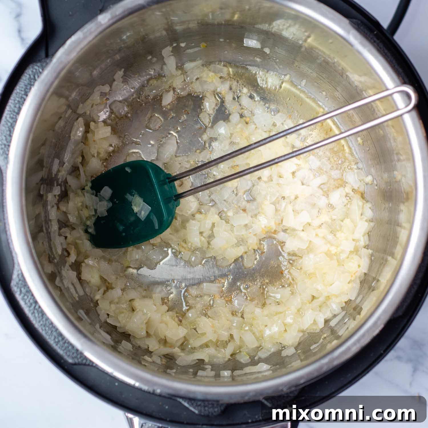 Diced onions and minced garlic sautéing in the Instant Pot liner, emitting a fragrant aroma.