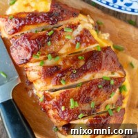 Overhead shot of golden-brown BBQ bacon wrapped chicken, garnished with fresh chives.