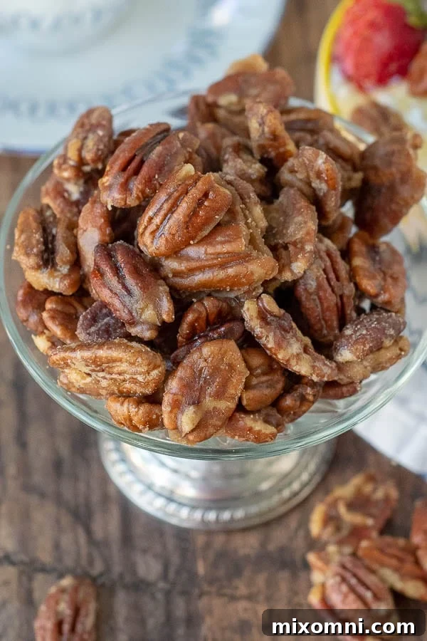 An overhead shot of glossy, golden candied pecans in an antique silver bowl, ready to be enjoyed.