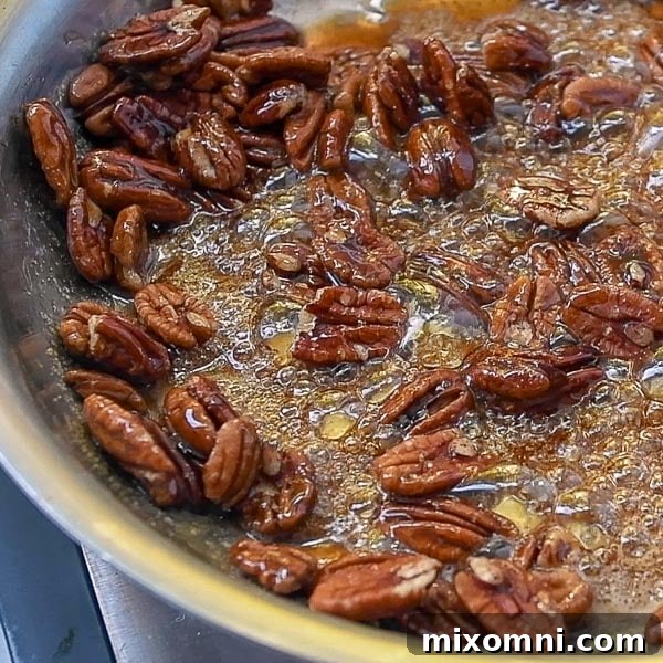 Second step of how to make candied pecans: stir in pecans to the bubbling syrup in the skillet.