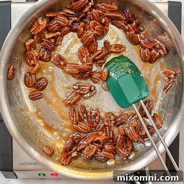 Third step of how to make candied pecans: continue cooking and stirring until the liquid syrup has reduced and thickened.