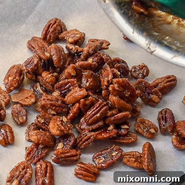 Fourth step of how to make candied pecans: pour the hot candied nuts onto a prepared baking sheet to cool and harden.