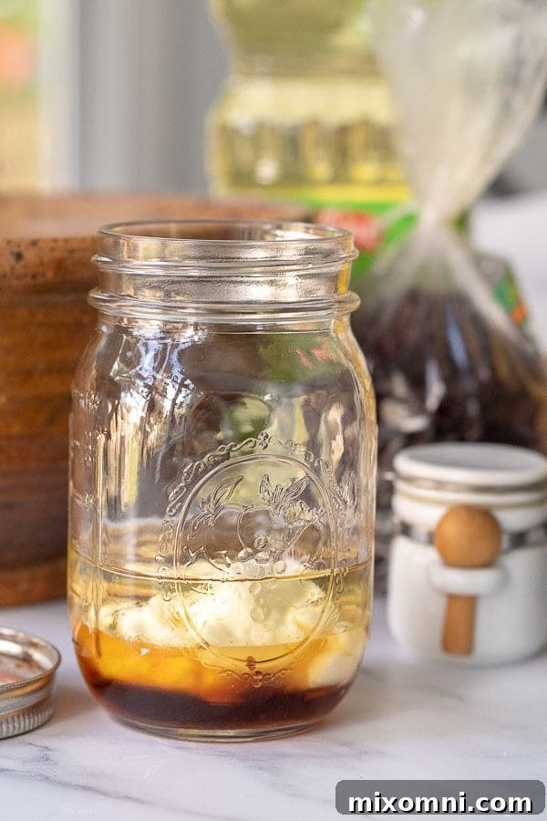 the ingredients for maple dressing in a glass ball jar