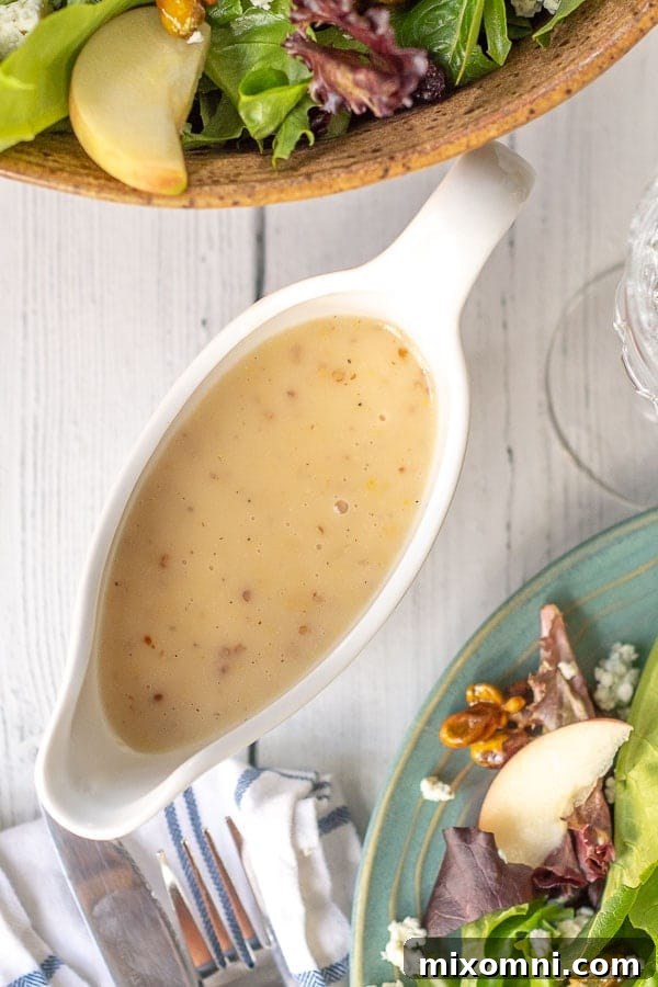 an overhead shot of maple vinaigrette with a plate of harvest salad next to it