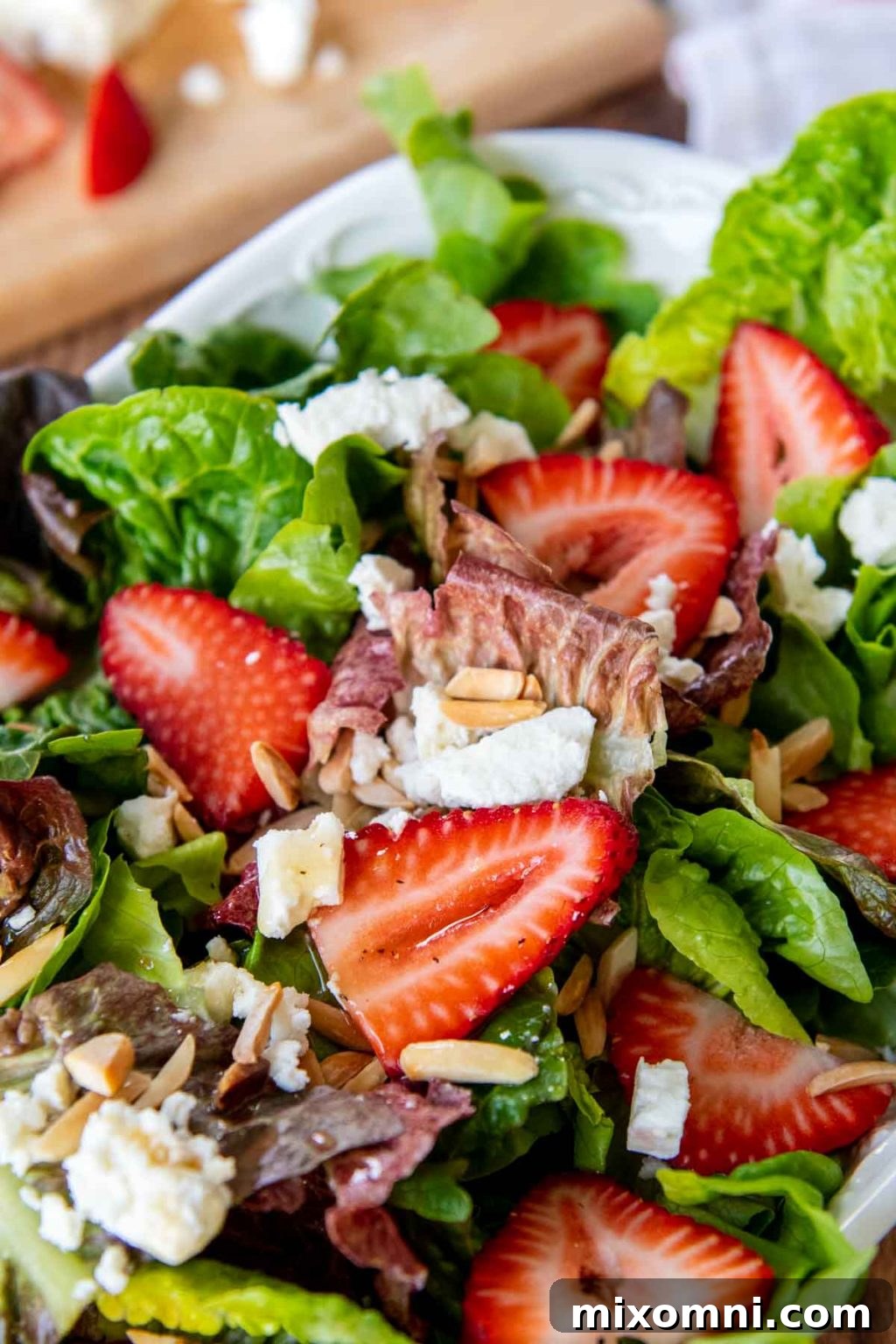 close up of strawberries and lettuce with dressing drizzled over top