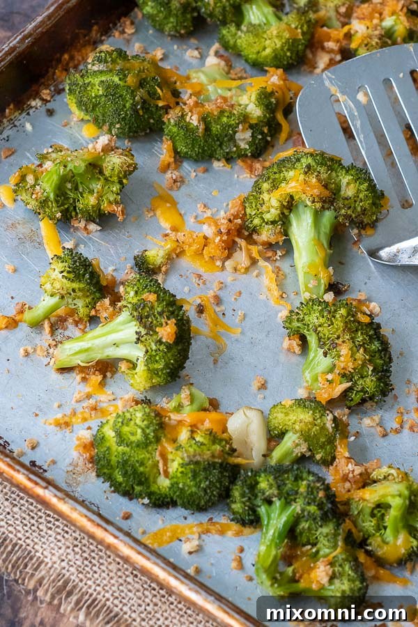 A close-up overhead shot of golden-brown baked broccoli and cheese on a baking sheet, ready to serve.