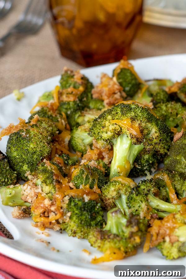 A generous serving of baked broccoli and cheese piled onto a white serving dish, steam gently rising.
