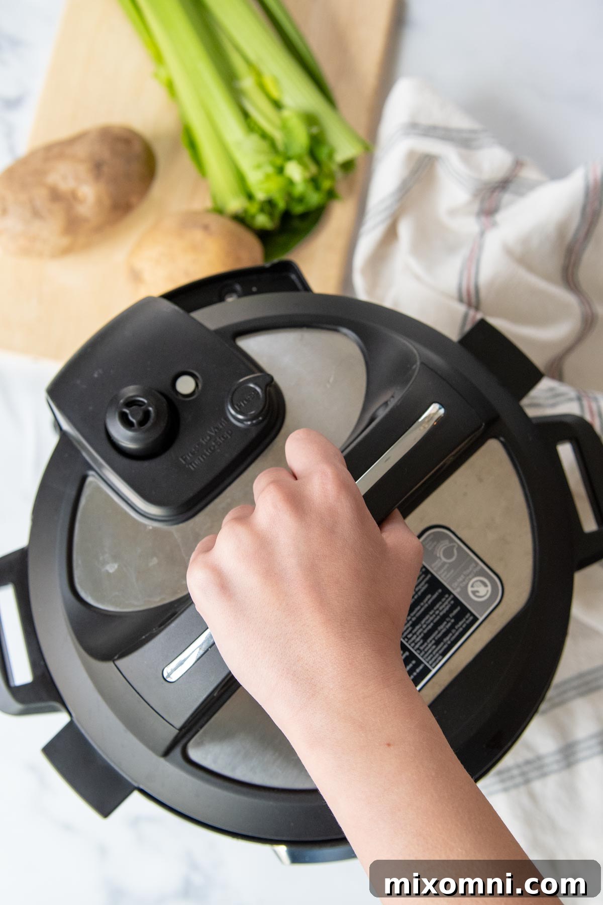 a hand opening a pressure cooker