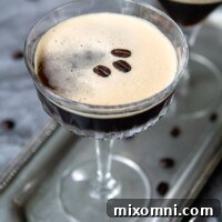 Two espresso martinis on a silver tray with espresso beans all around