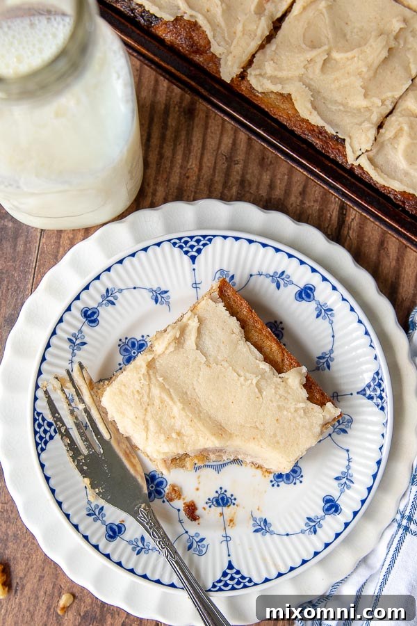 An inviting overhead shot of a frosted banana bread bar on a white and blue patterned plate, with a bite playfully taken out.