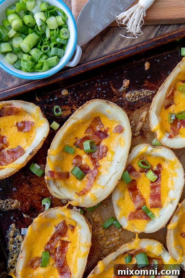 a close up overhead shot of potato skins on a baking sheet with cut green onions sprinkled around