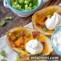 a close up of a loaded potato skin with a dollop of sour cream on top