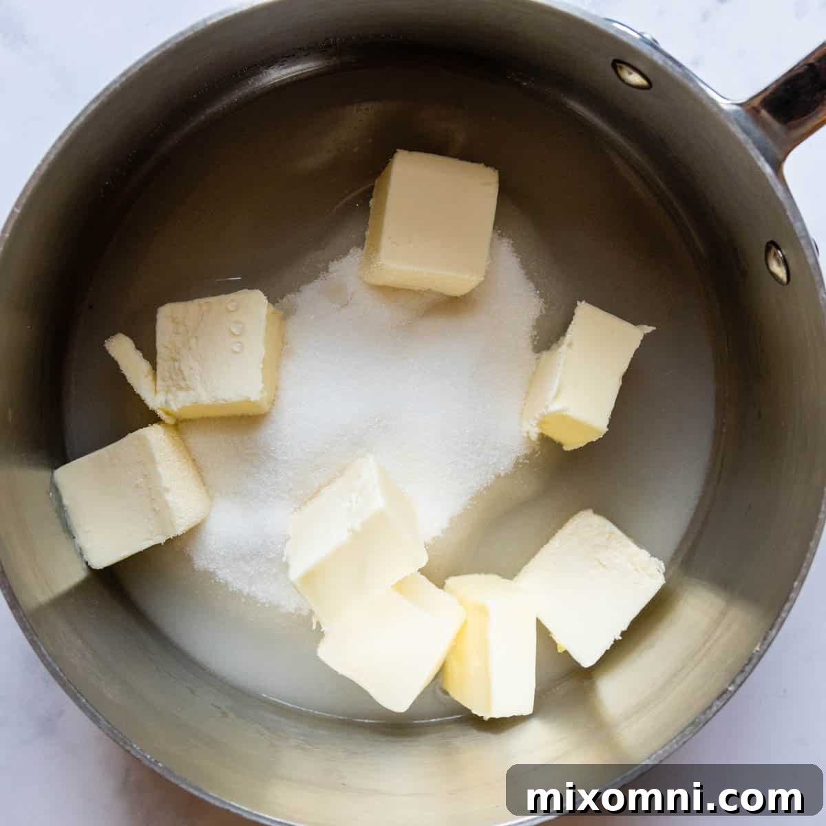 Cubed butter, granulated sugar, and water gently melting together in a saucepan over low heat.