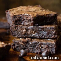 A stack of fudgy gluten-free brownies with a bite taken out of the top one.