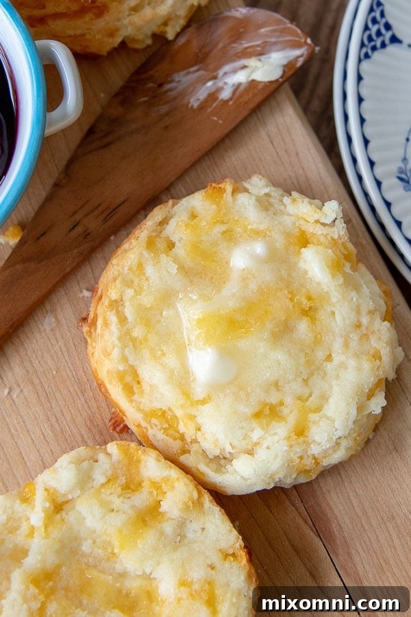 A warm gluten-free cheese scone sliced open, revealing its soft, tender interior with melted butter spread on top.