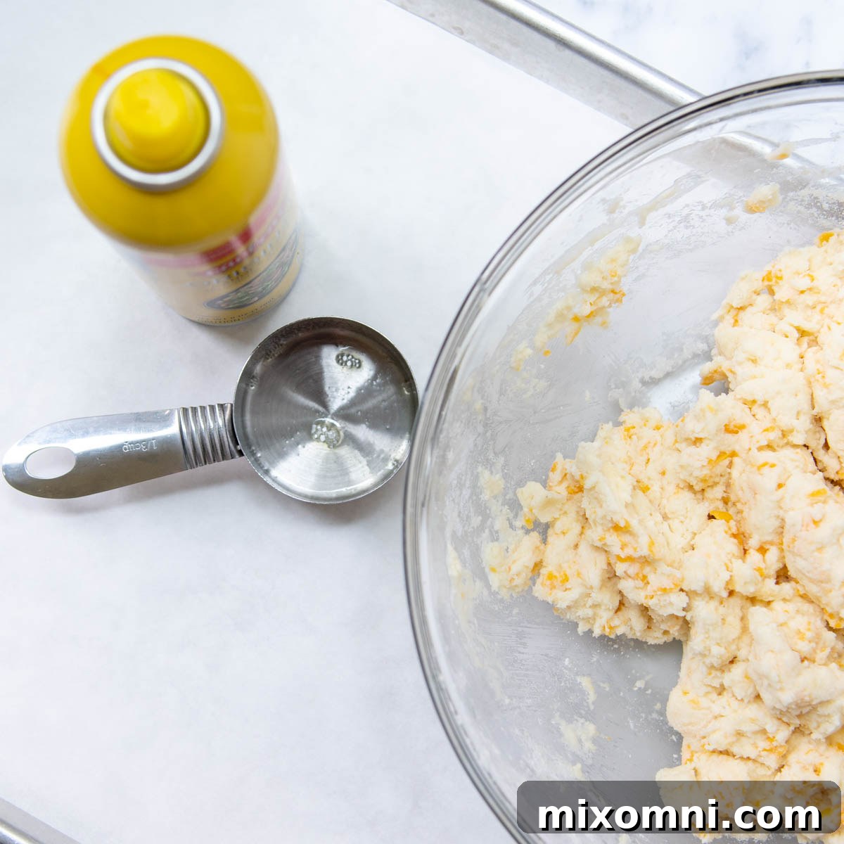 A greased 1/3 measuring cup filled with gluten-free scone dough, ready to be dropped onto the baking sheet.