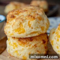 A stack of two gluten-free cheese scones on a wooden cutting board.